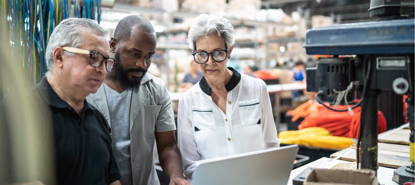 Employees Looking At Laptop In Factory